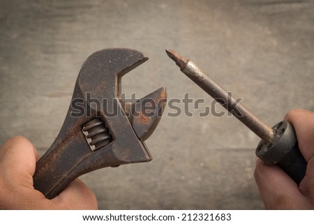 Mechanic hand hold pliers tool and screwdriver in hand isolated on wood background