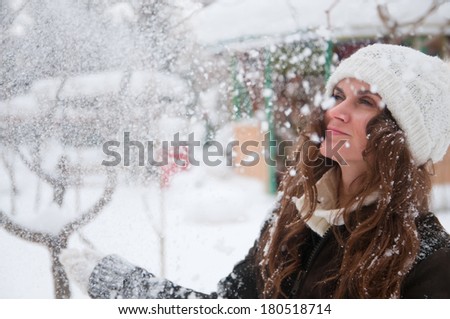 Beautiful girl throws snow in winter park