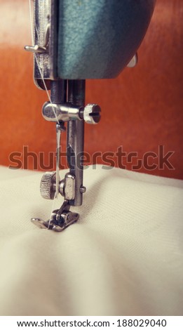 Fragment of an old sewing machine sews fabric ivory