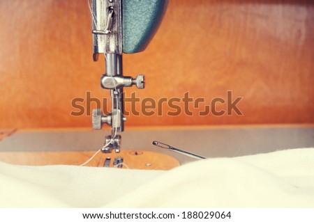 Fragment of an old sewing machine sews fabric ivory
