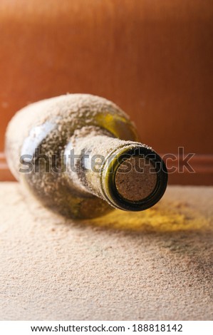 Vintage wine bottle, covered with dust on the wooden table