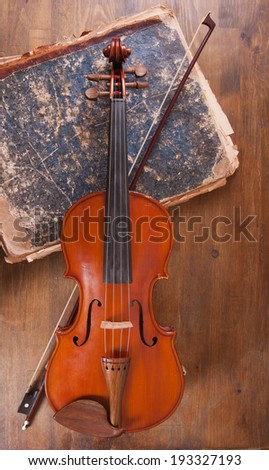Violin, bow and old book on a table