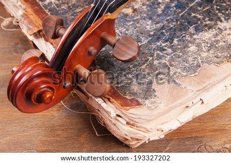 Violin, bow and old book on a table