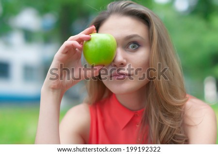 Portrait of beautiful girl with green apple in the park