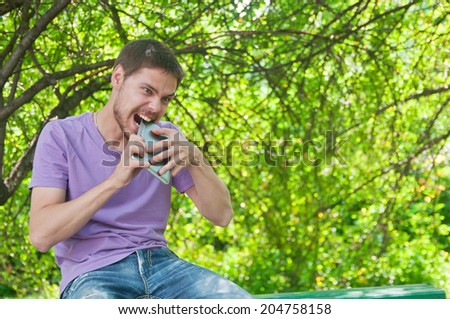 Young man angry old tablet computer in a summer park