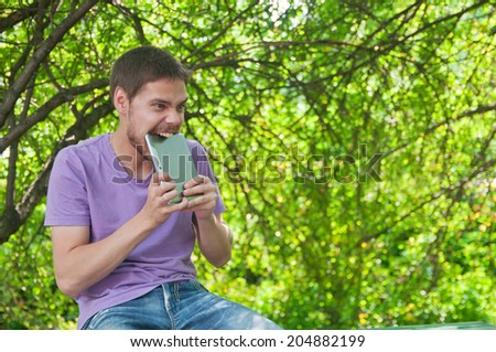 Young man angry old tablet computer in a summer park