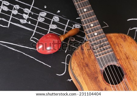 Vintage guitar and maracas on a chalkboard with music notes