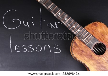 Old guitar on the chalkboard and the inscription \