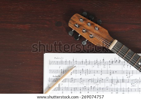 Music notes, vintage guitar and two pencils on table
