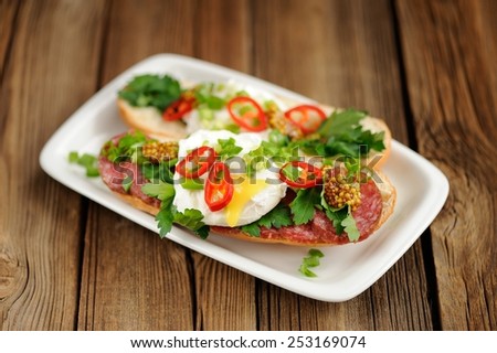 Poached egg sandwiches with chili, scallion and salami selective focus