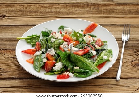 Spinach and blood oranges salad with cottage cheese and peanuts on wooden background with space