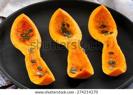 Cut butternut squash with pumpkin seeds on black tray