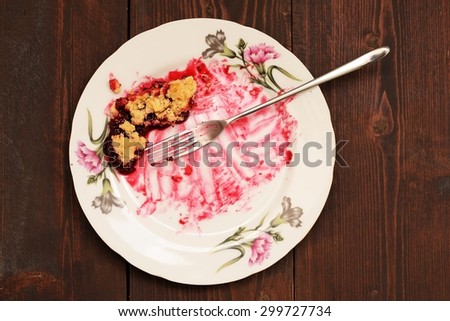 Remains of delicious cherry pie in white plate with long fork on wooden table