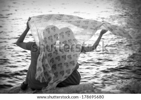 profiles in love at the beach with towel in the wind