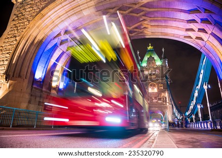 Tower Bridge in London, UK at night with moving red bus , long exposure