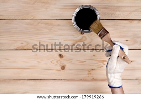 Brush in hand and painting on the wooden wall