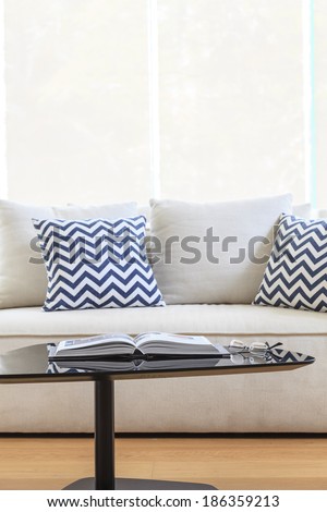 Living room sofa with pillows table book and eyeglass