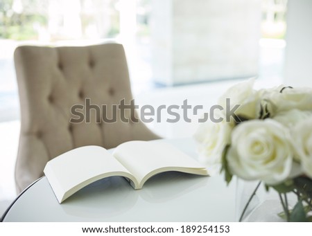 Book on table with white rose flower in living room