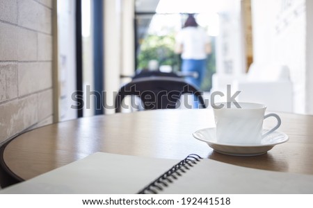 Table top with Cup of coffee and book in Cafe restaurant background with people