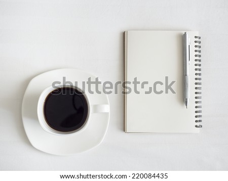 Cup of Coffee with Notebook and Pen on White Table Background