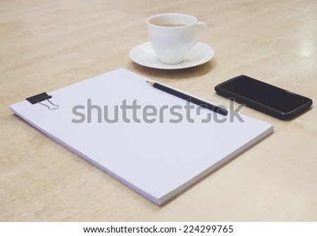 cup of coffee on working desk with paper pencil and mobile phone