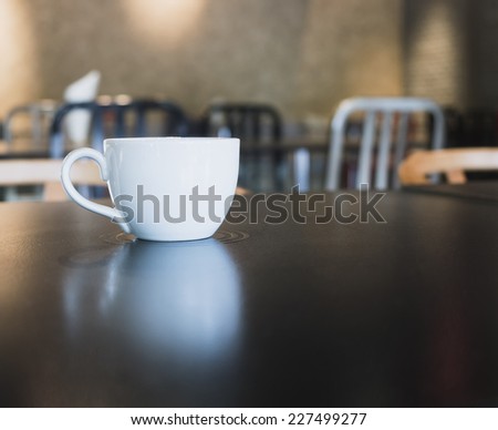 Cup of coffee on table with blurred cafe restaurant interior background