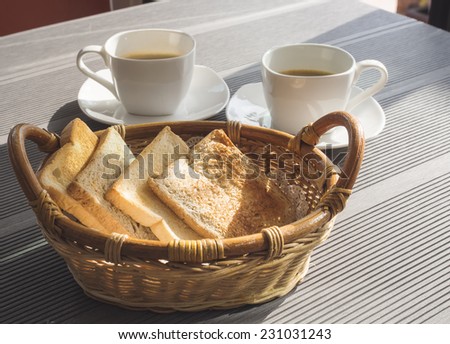 Breakfast toasted bread in basket with coffee on table