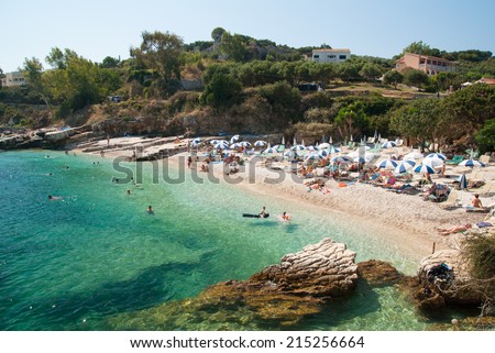 Kassiopi Beach, Corfu Island, Greece. Sunbeds and parasols (sun umbrella) on the beach.\
Tourists relaxing on beautiful beach of Kassiopi in the north area of Corfu Island.