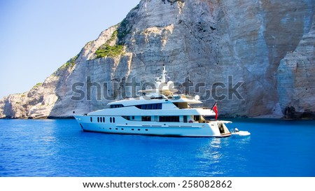 Luxury white yacht navigates into beautiful blue water near Zakynthos. View from the top of a large white yacht at Navagio Beach.