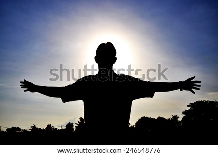 Silhouette of man open arms  with bright sun background