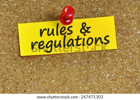 rules & regulations word on notepaper with brown cork background