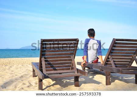 The man sit on beach chair on sand beach. Concept for rest, relaxation, holidays, spa, resort with copy space area.