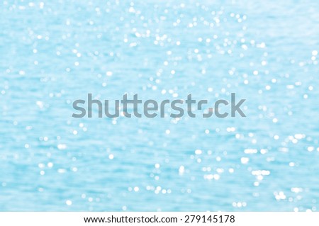 The Defocused Of Water surface with waves glittering in the sun. Out of focus bokeh of sun glares reflected