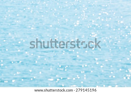 The Defocused Of Water surface with waves glittering in the sun. Out of focus bokeh of sun glares reflected