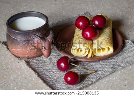 Breakfast of rolled pancakes with cherries and milk, still life