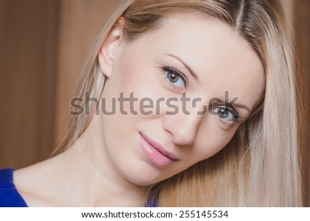 Portrait of beautiful young blond woman against wooden background, head shot