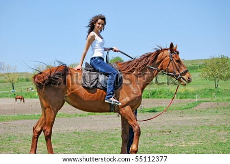 young and attractive woman riding brown horse