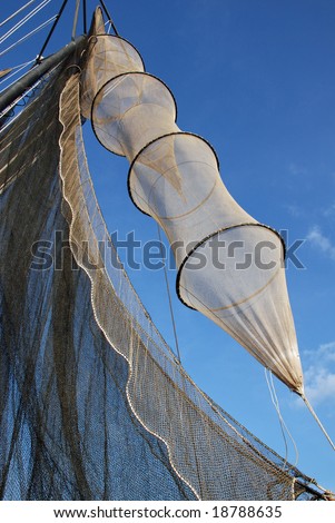 Fish traps and fishing nets drying in sun and wind on a trawler under a clear blue sky