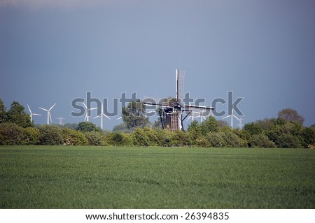 Old fashioned historical windmill surrounded by modern environmentally friendly windmills in a dutch landscape in Nisse in Zealand