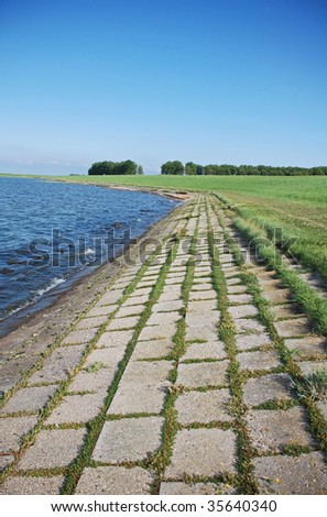 These concrete stones on a dutch dike in  nature reserve Oosterschelde with natural vegetation will be replaced  by a stronger safer material to protect the land against the  rising od the sea level