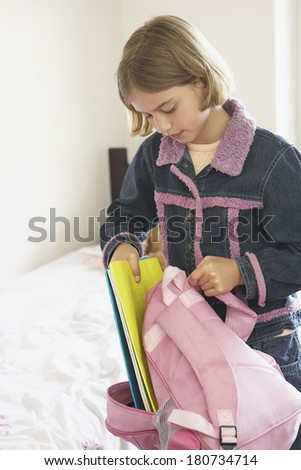 Young girl preparing her bag for school in the morning