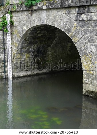 Old stone arched bridge with flood level marker showing the depth of the river