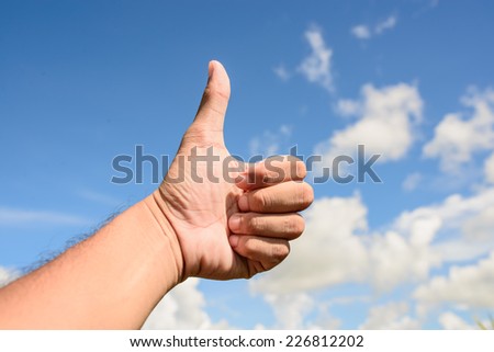 Image of several human hands showing thumbs up against clear blue sky