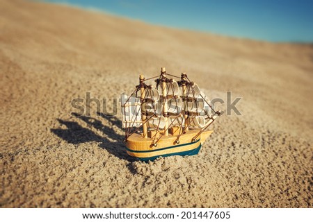 Sailing ship model on sand under blue sky