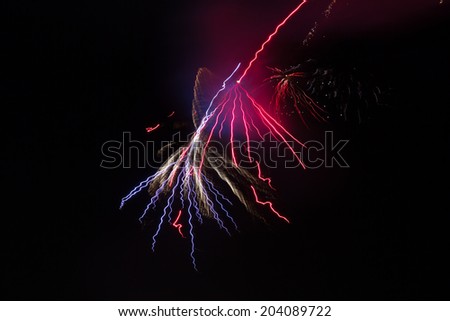 Isolated group of pink and red fireworks against night sky