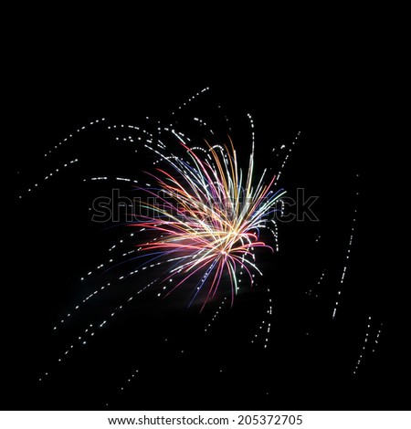 Burst of multi-colored fireworks with white streams of light against black sky background