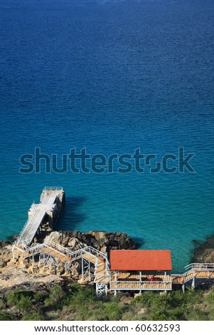 A view of a pier or jetty with wide open sea from a hilltop in portrait orientation.