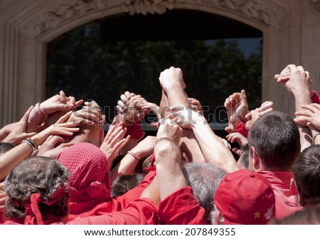 Joined hands to human tower.  Human Tower, typical tradition of Catalonia. Joined hands to concept binding, effort and solidarity.
