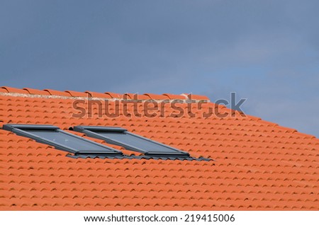 Modern house with roof windows and tiled roof on blue sky background