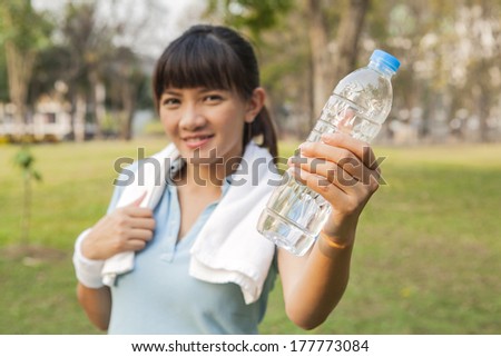 Asian sport woman smiling showing bottle of water in the park